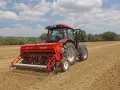 Trattore rosso con seminatrice Gasparardo in azione, un momento cruciale quando si semina il grano per il futuro raccolto.