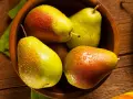 Pere succose in una ciotola di legno, pronte per essere gustate. Scopri come far maturare le pere per un sapore perfetto.