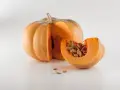 Zucca intera e una fetta con semi, un invito a pensare a quando piantare le zucche per un raccolto autunnale.