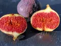 Fichi maturi, uno intero e due tagliati a metà, rivelano la loro polpa succosa. Ci si chiede dopo quanti anni fruttifica il fico per gustare queste delizie.