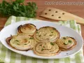 Cipolle di Giarratana al forno, cotte a spirale e guarnite con prezzemolo fresco, su un piatto bianco.