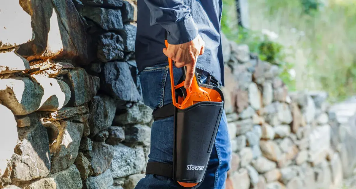 Uomo con forbici da potatura Stocker in fondina alla coscia, pronto per la potatura. Scopri come disinfettare le forbici da potatura per una cura ottimale delle piante.