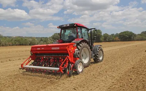 Trattore rosso con seminatrice Gasparardo in azione, un momento cruciale quando si semina il grano per il futuro raccolto.