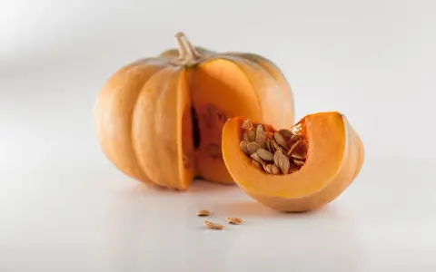 Zucca intera e una fetta con semi, un invito a pensare a quando piantare le zucche per un raccolto autunnale.