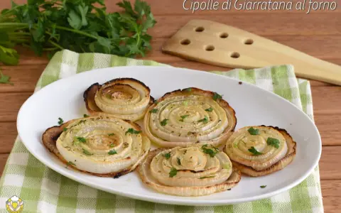 Cipolle di Giarratana al forno, cotte a spirale e guarnite con prezzemolo fresco, su un piatto bianco.