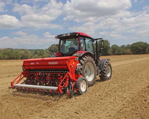 Trattore rosso con seminatrice Gasparardo in azione, un momento cruciale quando si semina il grano per il futuro raccolto.