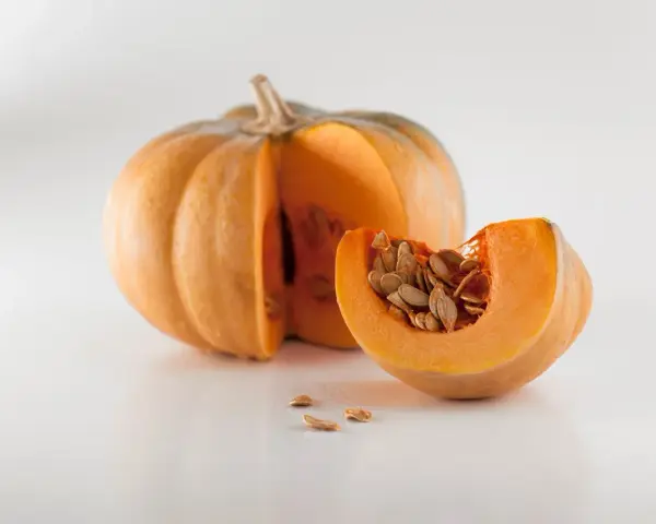 Zucca intera e una fetta con semi, un invito a pensare a quando piantare le zucche per un raccolto autunnale.