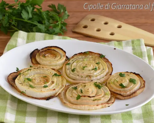 Cipolle di Giarratana al forno, cotte a spirale e guarnite con prezzemolo fresco, su un piatto bianco.