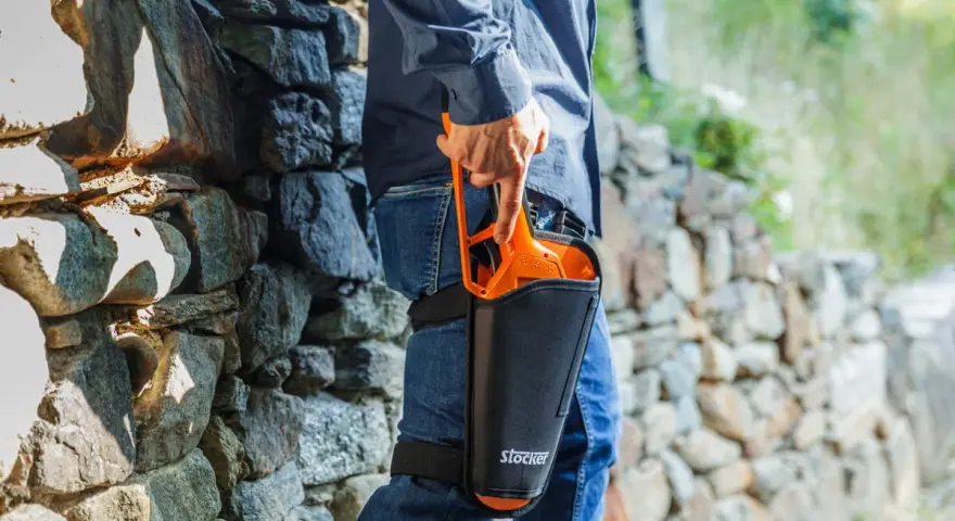 Uomo con forbici da potatura Stocker in fondina alla coscia, pronto per la potatura. Scopri come disinfettare le forbici da potatura per una cura ottimale delle piante.