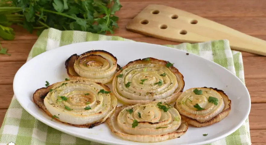 Cipolle di Giarratana al forno, cotte a spirale e guarnite con prezzemolo fresco, su un piatto bianco.