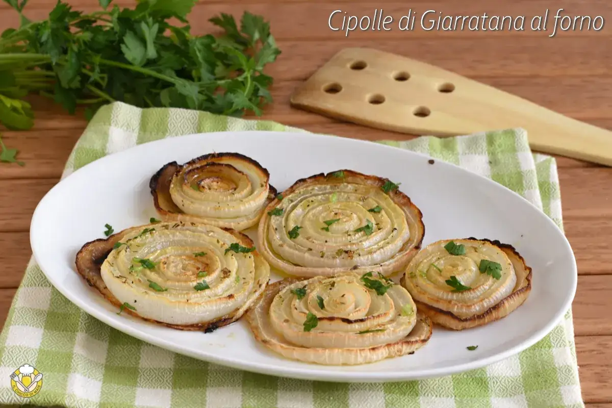 Cipolle di Giarratana al forno, cotte a spirale e guarnite con prezzemolo fresco, su un piatto bianco.